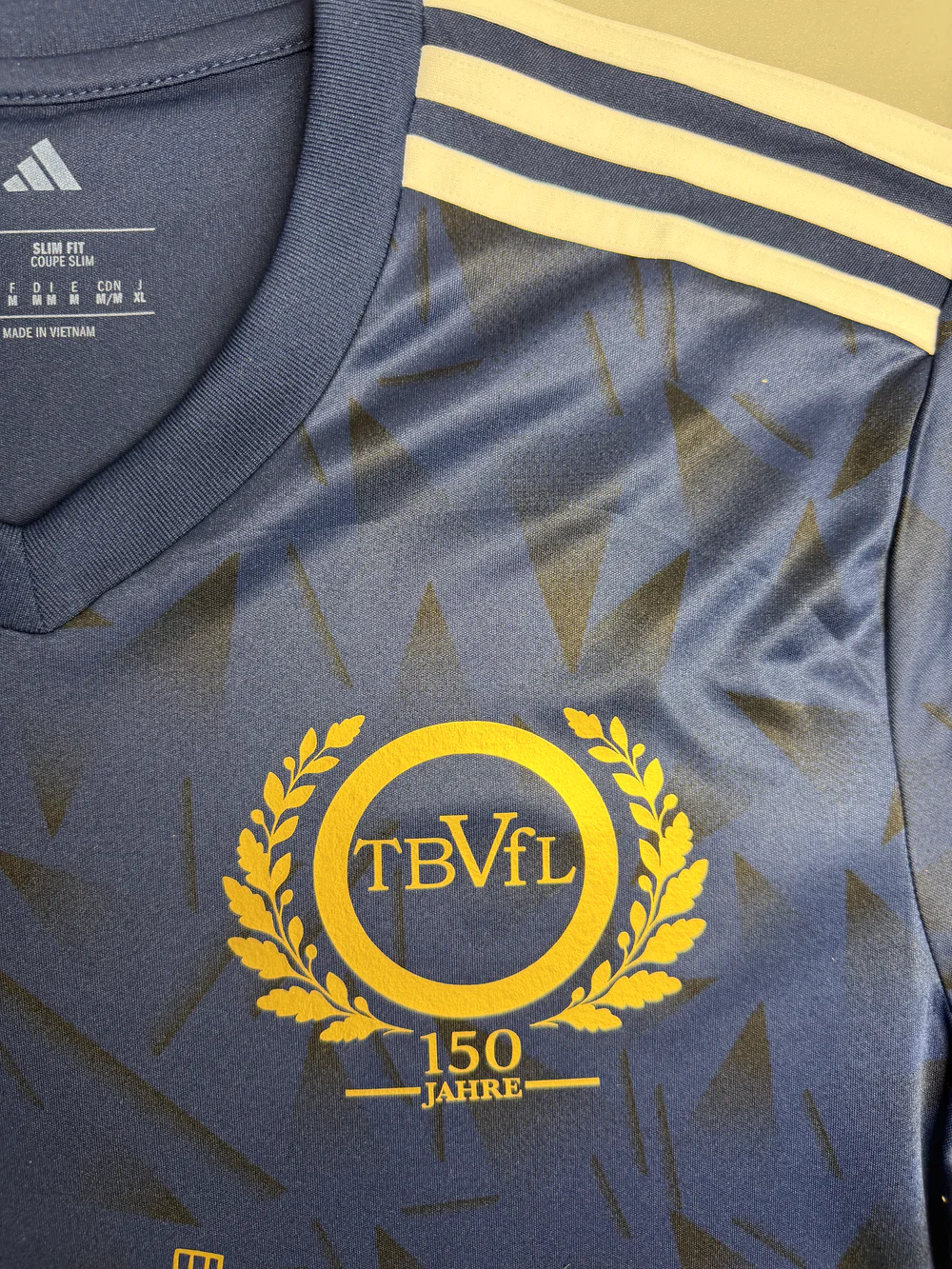 Modifiziertes goldenes TBVfL-Jubiläumslogo mit Lorbeerkranz und Schriftzug 150 Jahre auf dunkelblauem Trikot